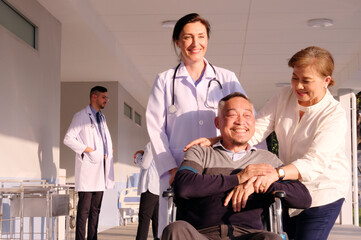 Fototapeta premium Female doctor cares for elderly male patient in wheelchair in hospital.