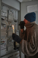 Checking the electricity power meter with a candle in cold winter season.