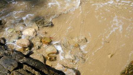 Outdoor beach, water waves, natural stones from top view
