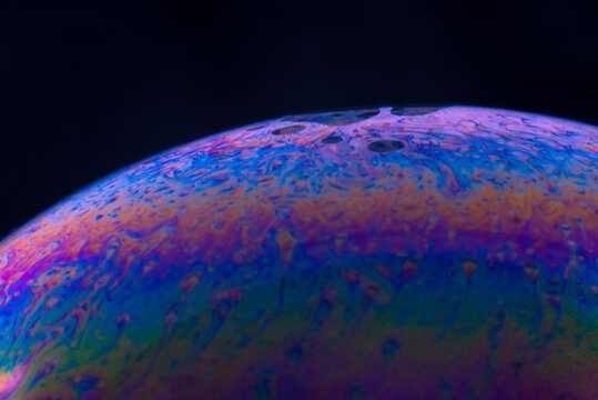 A macro photography of soap bubble in dark which is so colorful and abstract looking.