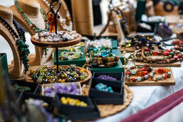 display of handmade jewelry with colorful gemstone necklaces and beads arranged on wooden trays and stands. The collection features an array of textures and hues, showcasing artisan craftsmanship.