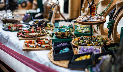 display of handmade jewelry with colorful gemstone necklaces and beads arranged on wooden trays and stands. The collection features an array of textures and hues, showcasing artisan craftsmanship.