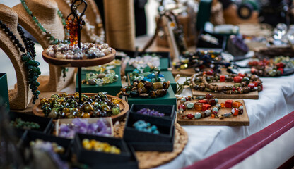 display of handmade jewelry with colorful gemstone necklaces and beads arranged on wooden trays and stands. The collection features an array of textures and hues, showcasing artisan craftsmanship.