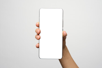 Hand with phone on white background with copy space. Woman holding smartphone with white screen. Hand with blank cellphone display, close-up