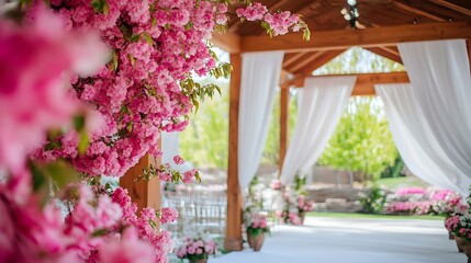A spring garden wedding venue with vibrant pink blossoms, soft white drapes, and natural wooden accents.