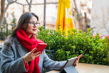 Businesswoman using cell phone with tablet in cafe. Remote work