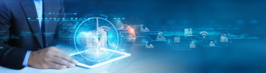 Smart City. Businessman holding and using a digital tablet device with Smart City Infrastructure, Connected Services Including IoT Applications, Urban Development and Modern Technology concept.