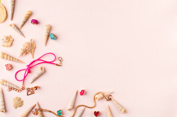Seashells and jewelry on pastel pink and green background. Pastel flat lay featuring seashells and colorful jewelry.