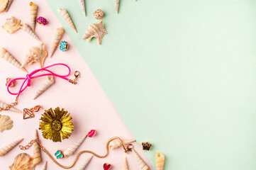 Seashells and jewelry on pastel pink and green background. Pastel flat lay featuring seashells and...