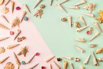 Seashells and jewelry on pastel pink and green background. Pastel flat lay featuring seashells and colorful jewelry.