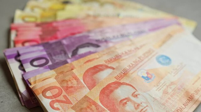 Philippine banknotes of various denominations spread out on a concrete surface showcasing vibrant colors and detailed prints of historical figures.