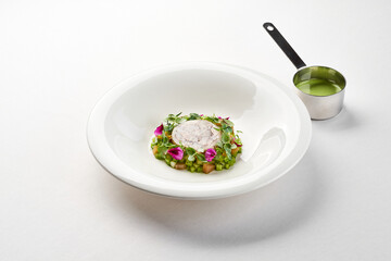 Dish featuring a delicate piece of fish, surrounded by a vibrant arrangement of fresh vegetables and edible flowers. The plate is garnished green sauc