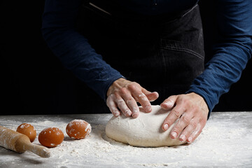 Fototapeta premium Male hands knead the dough for bread, pasta or pizza, close up. Closeup hand of chef baker kneading a dough