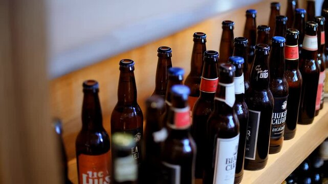 Rotating closeup of a variety of beer bottles on a wooden shelf - Powered by Adobe