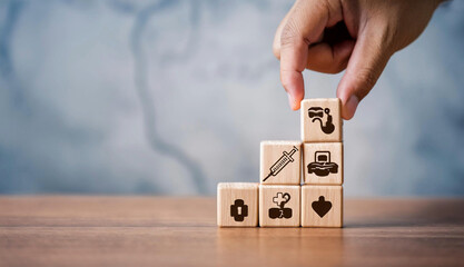 Health insurance concept represented by a hand arranging wooden cubes with healthcare and medical icons on a wooden background. Perfect for illustrating financial planning, healthcare coverage,