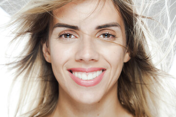 Joyful young woman with flowing hair and a bright smile, studio shot