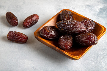Large dates fruit in a wooden bowl on bright background