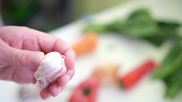 close up of unrecognizable male hands chopping garlic on board. Man's hands cutting garlic with a knife over cutting board. Making food at home, homemade