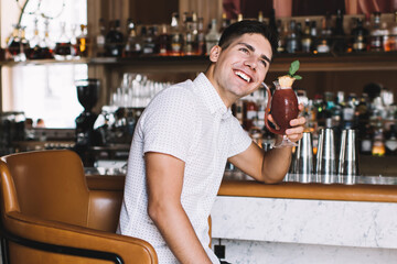 Happy man sitting with glass of drink in bar