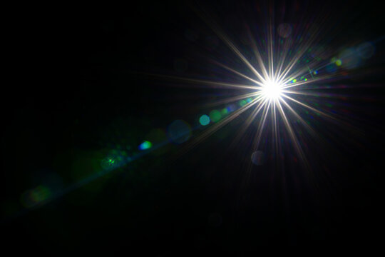 shiny sun with sunbeams and lens flares isolated on black background, bright texture overlay template decoration and graphical design element