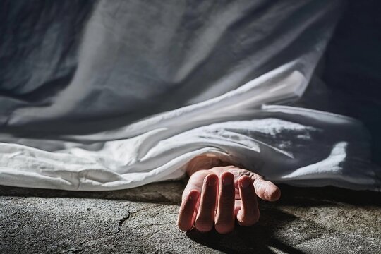 Hand of dead body covered by white sheet,horror and crime scene.