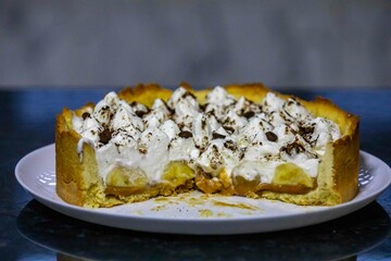 Traditional banoffee cake with banana and caramel sauce filling sprinkled with grated dark chocolate and coffee . English traditional pie