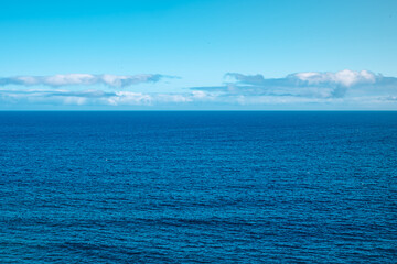 Obraz premium The ocean is calm and clear, with no clouds in the sky. The water is a deep blue color, and the sky is a bright blue color