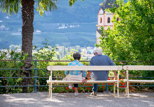 Meran, Tirol - Ein paar Senioren auf dem ber&uuml;hmten Tapeinerweg rasten mit Blick auf die St. Nikolauskirche und das Stadtzentrum