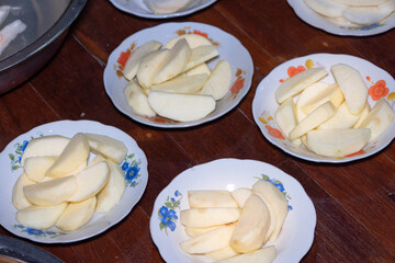 Peeled and cut apples are placed on a plate and arranged in rows.