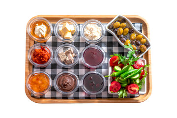 Traditional Turkish Breakfast with Olives, Honey, Clotted Cream, Jam, and Fresh Vegetables on a Wooden Tray
