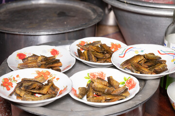 Dried fish is fried and placed on a plate for breakfast.