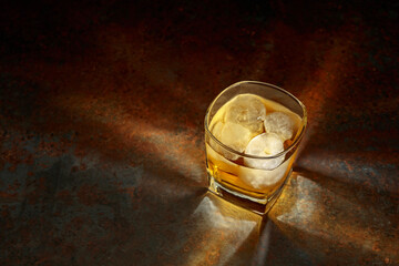 Whiskey in a square glass with ice on a vintage background.