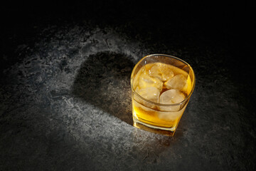 Whiskey in a crystal glass with ice on a old stone table.
