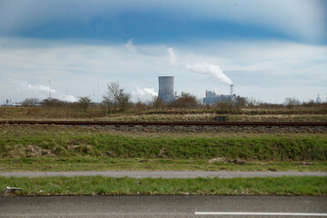 Power plant operating in a rural area under a cloudy sky with steam emissions in the background