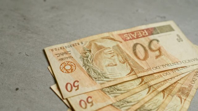 Brazilian banknotes of 50 reais arranged on a concrete surface, highlighting the brazilian currency in a modern setting.