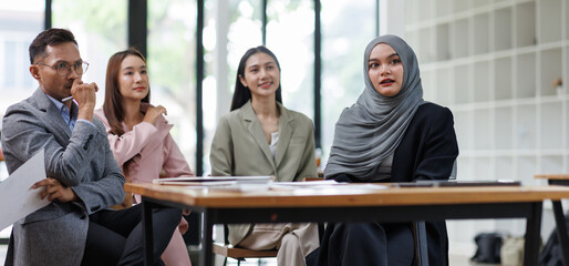 Business Asian people, laptop and conversation with research, teamwork and connection in the office. Group, employees and accounting with computer, internet and cooperation with meeting and planning