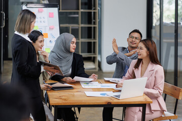 Business Asian people, laptop and conversation with research, teamwork and connection in the office. Group, employees and accounting with computer, internet and cooperation with meeting and planning