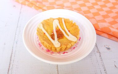 mini pies with colorful toppings on a white plate. small tart cakes and pies on white table background with orange napkins, top view