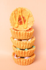 mini pies with colorful toppings. small tart cakes and pies isolated on pink background. Small cupcakes with colorful chocolate toppings, copy blank space