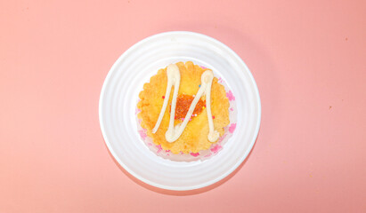 mini pies with colorful toppings. small tart cakes and pies on white plate isolated on pink background. Small cupcakes with colorful chocolate toppings, copy blank space