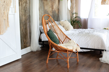 Interior boho design bedroom with garland flowers and plants. Cozy light bedroom in Scandinavian style bedroom, canopy bed and wicker rattan armchair. Bed decorated flowing white curtains canopies.   © stock_studio