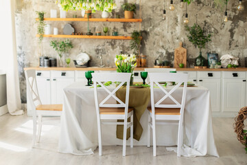 Interior design scandinavian kitchen with table and chair. Cozy Wooden white cuisine decorated with flowers and decor. Kitchen utensils, dishes, plates on shelves. Stylish dining room with furniture	
