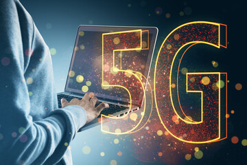 Person using laptop with glowing "5G" sign overlay, representing advanced digital technology and internet communication.