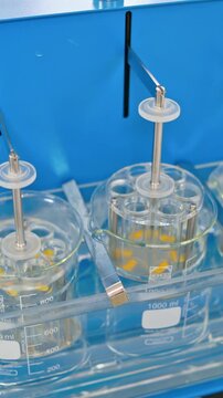 Experiments at the lab. Sliding shot of a dissolution apparatus testing medication pills dissolving tablets in liquid. Laboratory routine. Vertical video