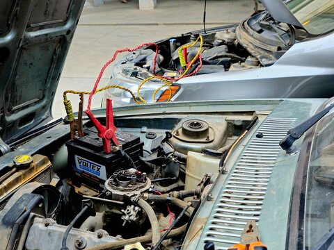Cairo, Egypt, December 24 2024: Jump starting by a booster cable, a car with a dead discharged battery made to start by supplying it with power from an external source of battery of another car