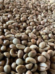 A top-down view of raw coffee beans before roasting, captured during the daytime at a coffee shop.