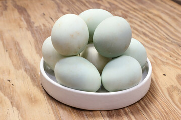 Pastel-Colored Eggs in a White Bowl on Wooden Surface