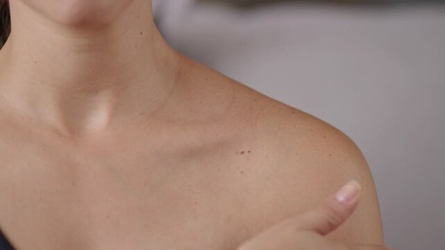 Young  woman with clean skin touching her shoulders and collarbones by the hand close up. Concept of skin care for health and beauty
