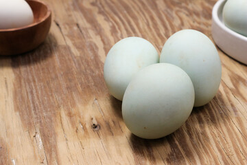 Three Pastel Blue Eggs on Rustic Wooden Table