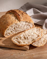 Freshly baked whole grain bread on a wooden cutting board with slices arranged beside it.